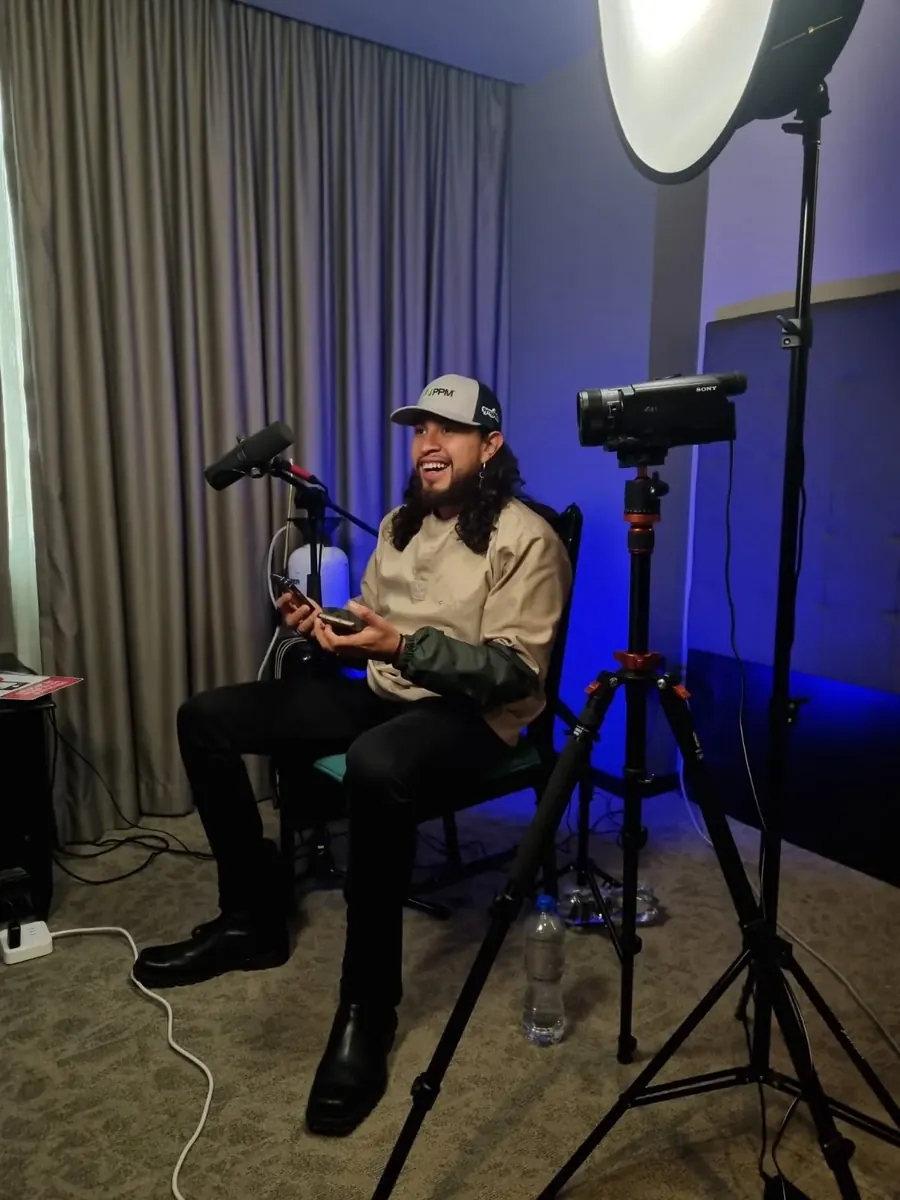 Daniel Torres, el Fumigador Bonito, controlador de plagas en la CDMX, sonriendo en el set de un podcast con micrófono, cámara y luces